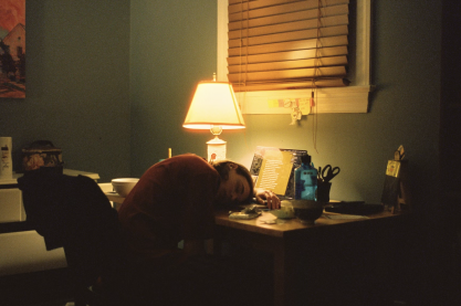 Girl sleeping with her head on a messy desk